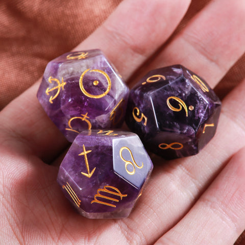 Three purple amethyst astrology dice with engraved gold symbols